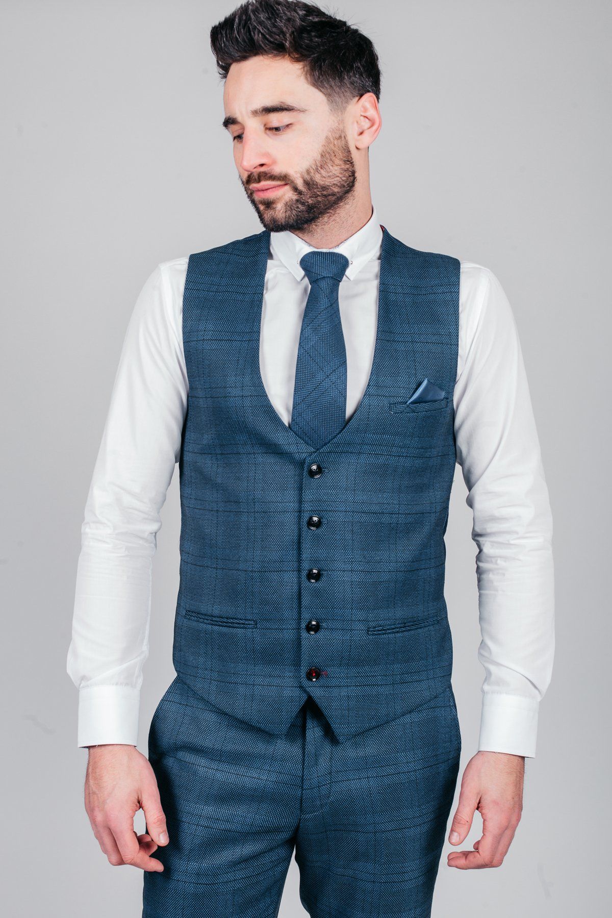 A man wears marcdarcy’s The Sheffield Utd Collection: Oliver Norwood in a Jerry Check Suit—featuring a teal plaid vest, matching teal plaid pants, white dress shirt, and teal tie.