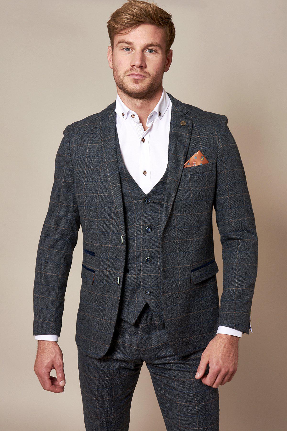 GMB Weather Presenter Alex Beresford wears the marcdarcy Scott Blue Tweed Check Suit—a vintage-inspired three-piece—paired with a white shirt and brown pocket square, standing against a plain beige background.