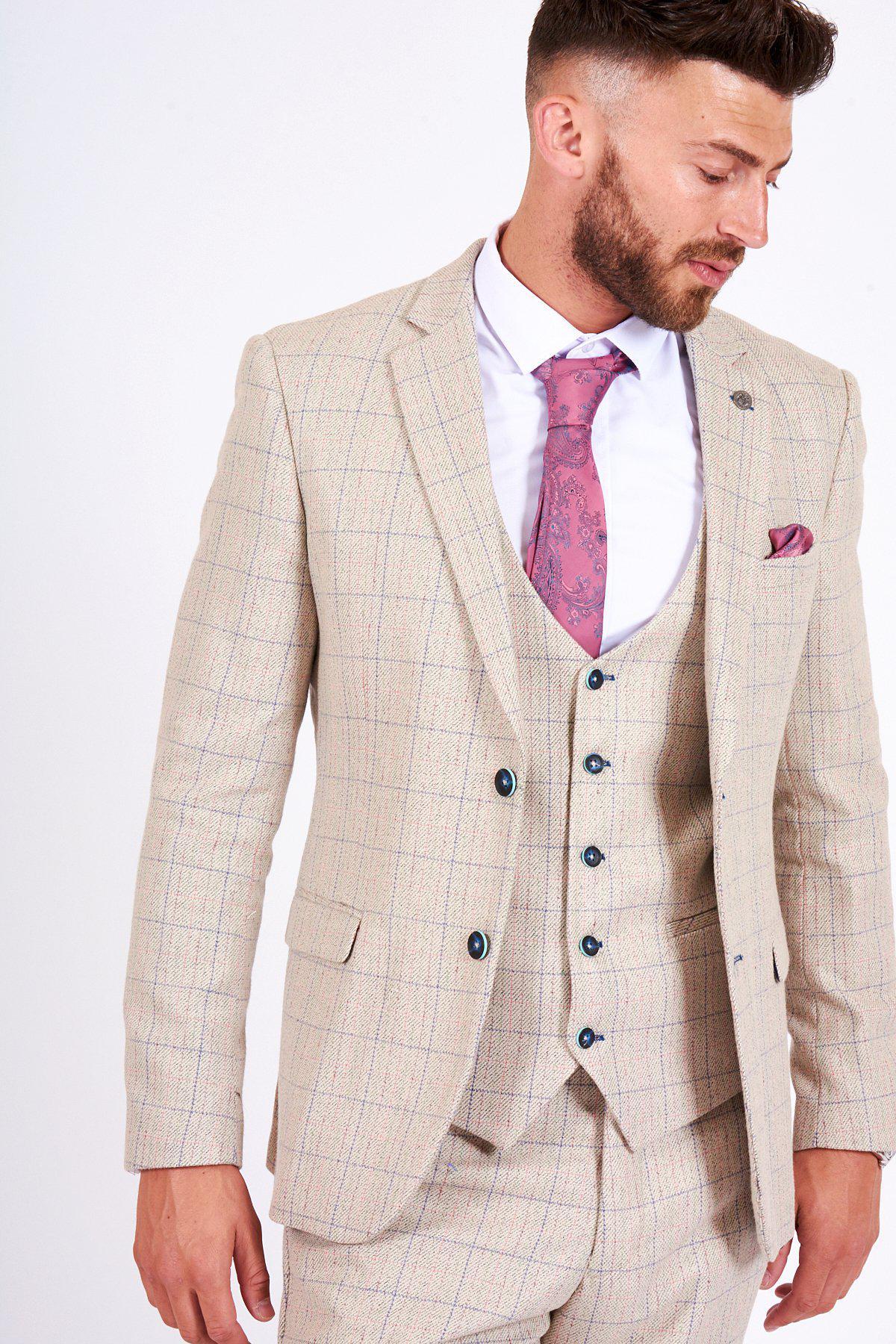 A man with short brown hair and a beard wears the marcdarcy HARDING - Cream Tweed Check Print Blazer, paired with a white shirt, pink tie, and matching pocket square, looking slightly down and to his left.