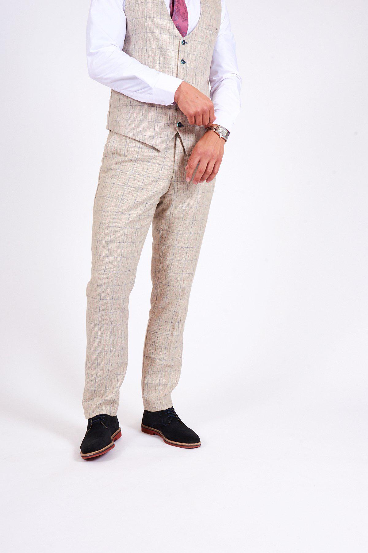 A person models marcdarcy’s HARDING Cream Tweed Check Print Trousers, paired with a matching vest, white shirt, pink tie, and black shoes against a plain white background. The model is looking at their wristwatch; their face is not visible.