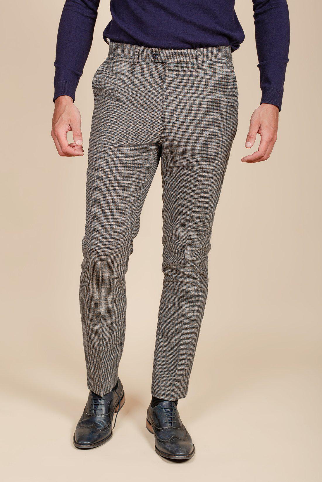 A person models marcdarcy HARDWICK Navy Tan Tweed Check Trousers with a dark long-sleeve shirt and black dress shoes against a plain beige background, focusing on the lower half of the body.