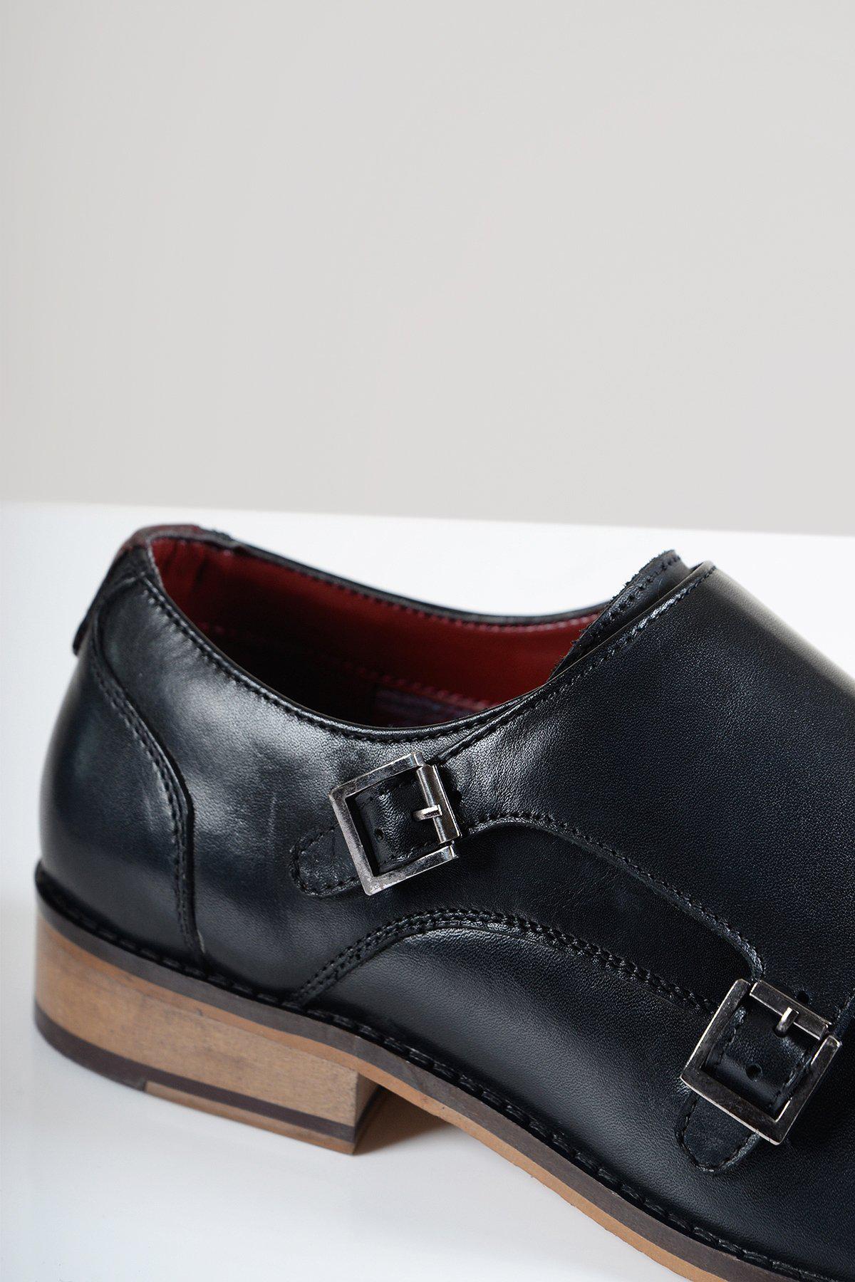 Close-up of the HARRIS Black Leather Double Strap Monk Shoe by Marc Darcy, featuring full grain leather, double silver buckles, a brown wooden sole, and a striking red interior lining against a light plain background.