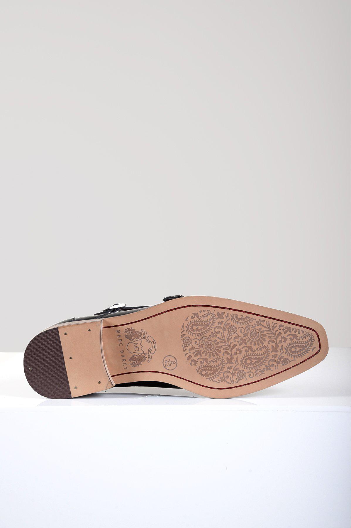 The HARRIS Black Leather Double Strap Monk Shoe by Marc Darcy is shown on its side, revealing a light brown sole engraved with an intricate floral pattern.