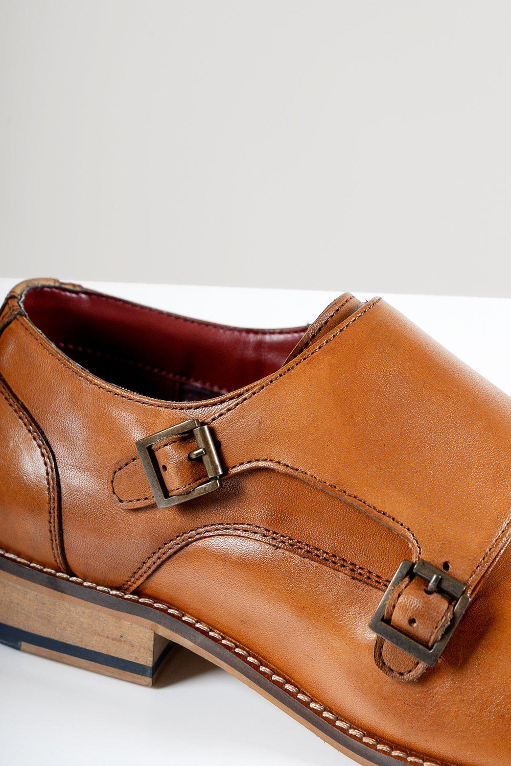 Close-up of the Marc Darcy HARRIS Tan Leather Double Strap Monk Shoe, featuring dark metal buckles, hand-stitched detail, and a wooden sole, set against a plain light background.