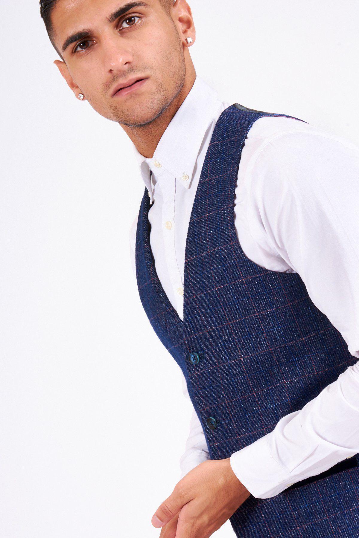 A man wears a white dress shirt and the marcdarcy HARRY Indigo Single Breasted Tweed Check Waistcoat. He has dark hair and earrings.