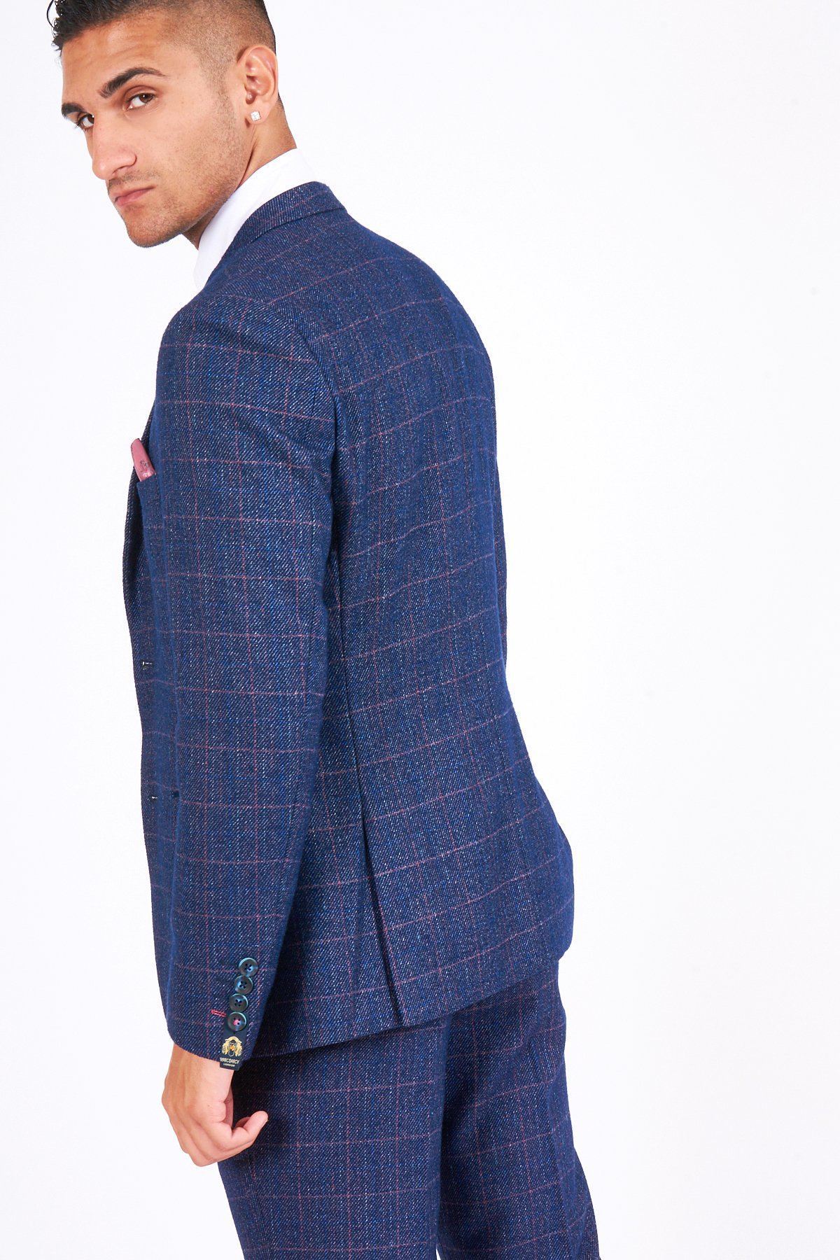 A man in the marcdarcy HARRY - Indigo Tweed Check Blazer stands slightly turned from the camera, glancing back over his shoulder. He has short hair, wears a white shirt underneath, and is set against a plain white background.