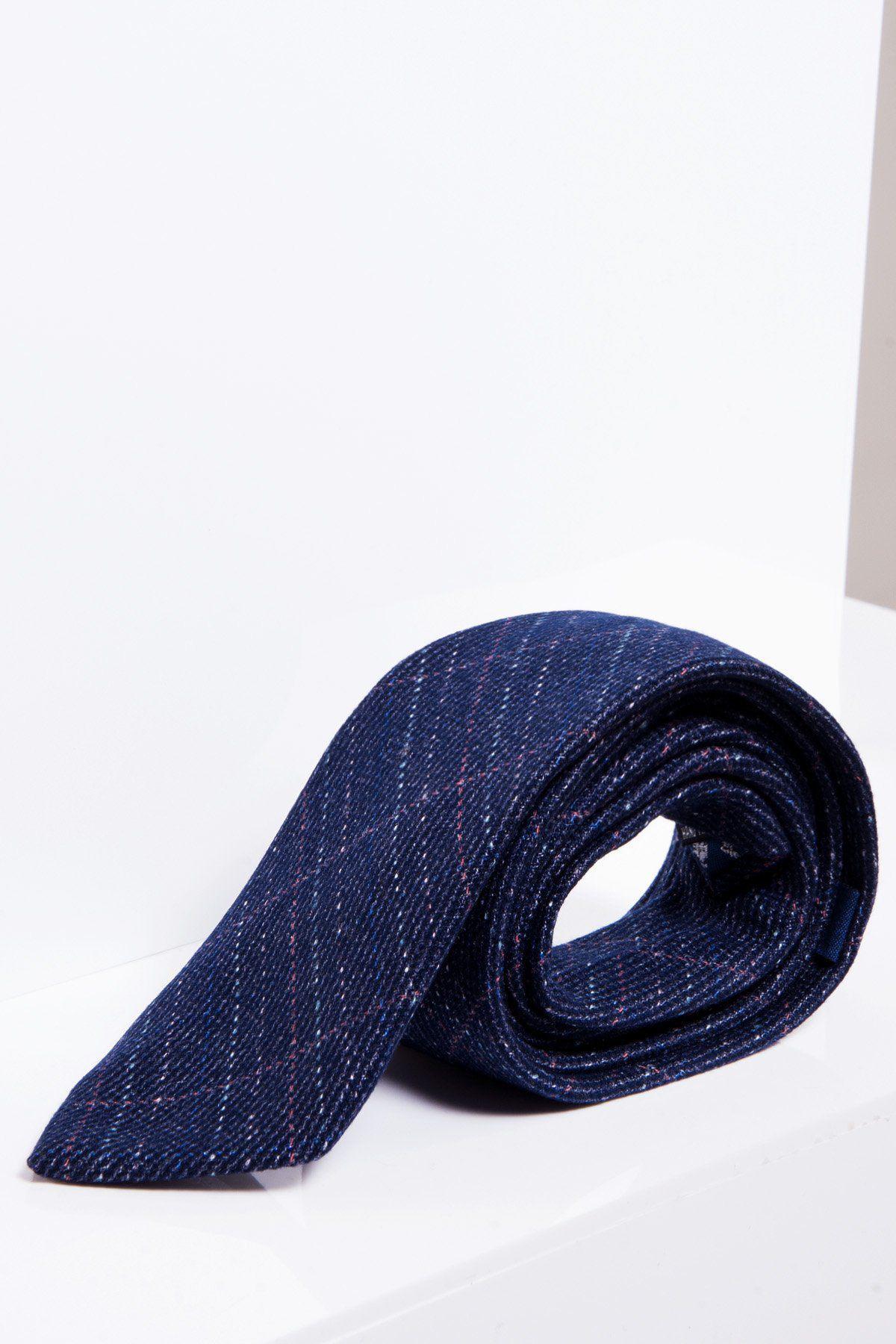The marcdarcy HARRY - Indigo Tweed Check Tie, in dark blue with a refined check pattern, is rolled up and displayed on a white surface—an ideal accessory for formal occasions.