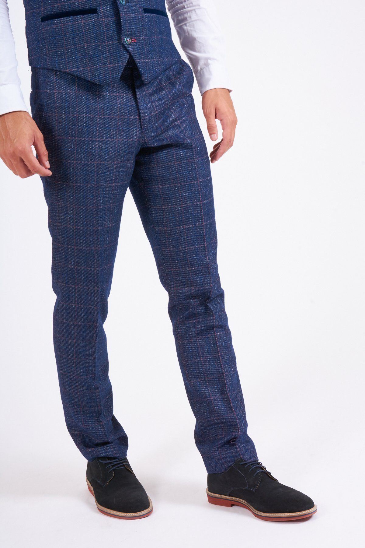 A person stands against a plain white background wearing a white shirt, marcdarcy's HARRY Indigo Tweed Check Trousers, a matching vest, and black dress shoes.