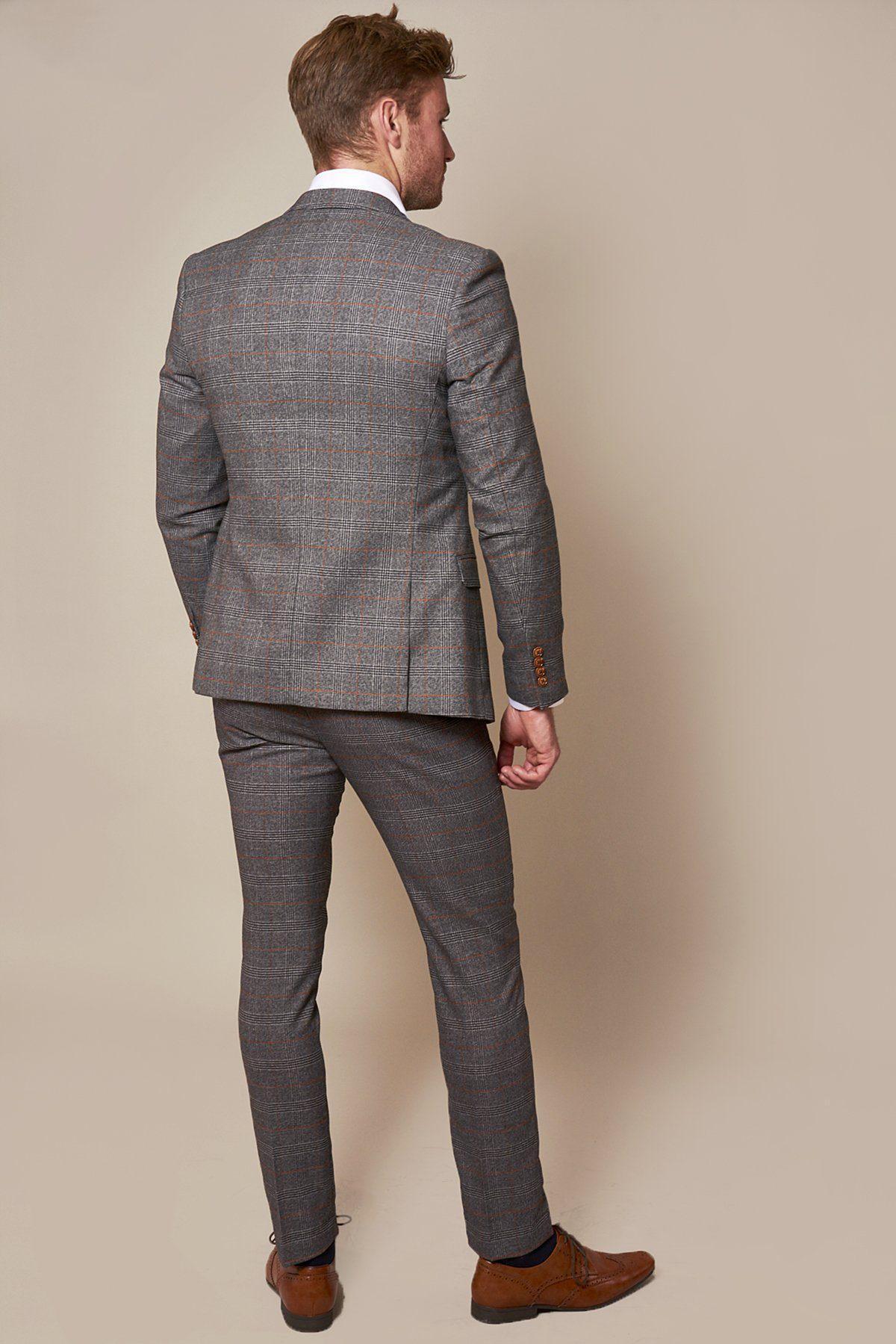A man models the marcdarcy Sheffield Utd Collection Billy Sharp Jenson Grey Check Suit with brown shoes, standing with his back to the camera against a plain beige background.