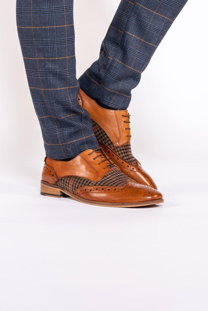 A person wearing blue plaid pants and Marc Darcy JACOB - Tan Leather Tweed Contrast Brogue Shoes stands against a white background.