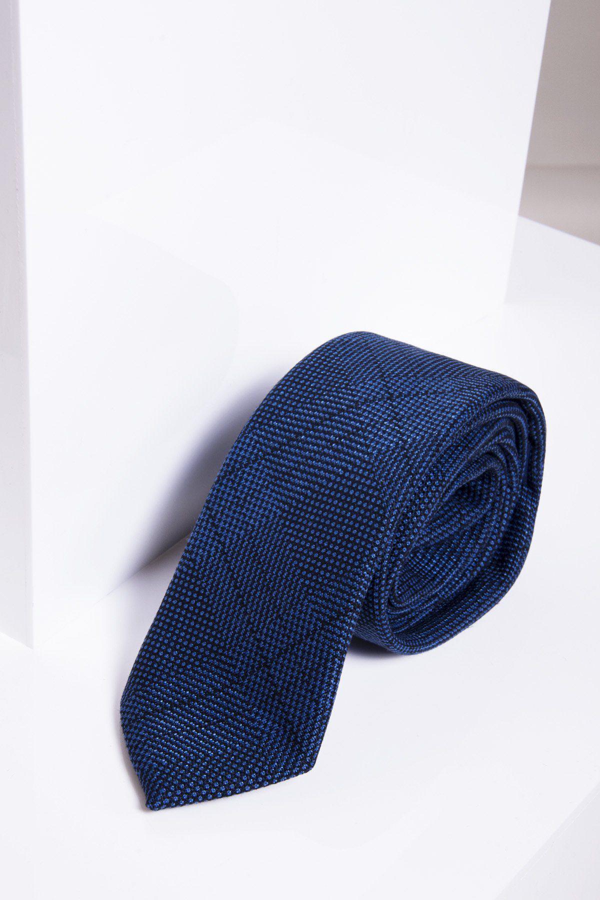 The JERRY - Blue Check Tie by marcdarcy is displayed on a white surface, showing off its monogrammed lining with a white geometric shape behind it.