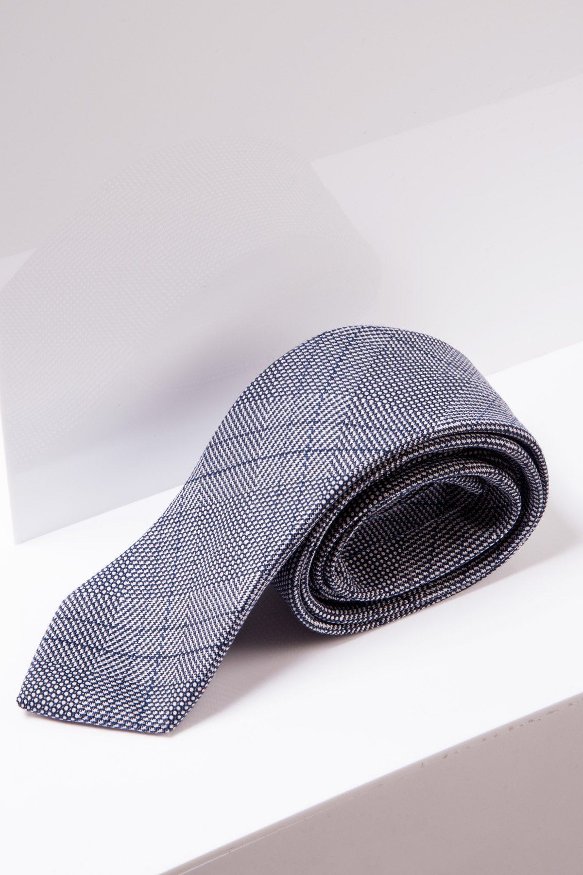 The marcdarcy JERRY - Grey Check Tie is neatly rolled and displayed on a white surface with a minimal background.
