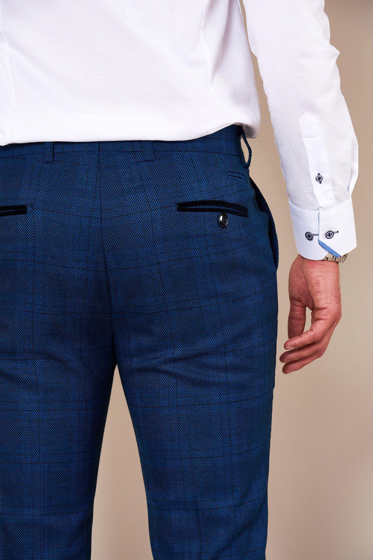 A person is shown from the back wearing a white dress shirt and marcdarcy JERRY Skinny Fit Blue Check Trousers, featuring black buttoned back pockets. Their right arm is relaxed at their side.