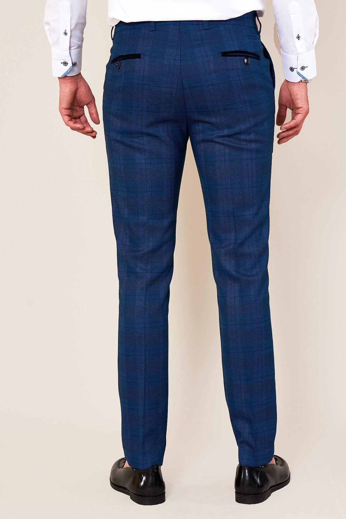 A man stands against a plain light background wearing a white dress shirt, marcdarcy JERRY Skinny Fit Blue Check Trousers with black buttoned pockets, and black dress shoes.