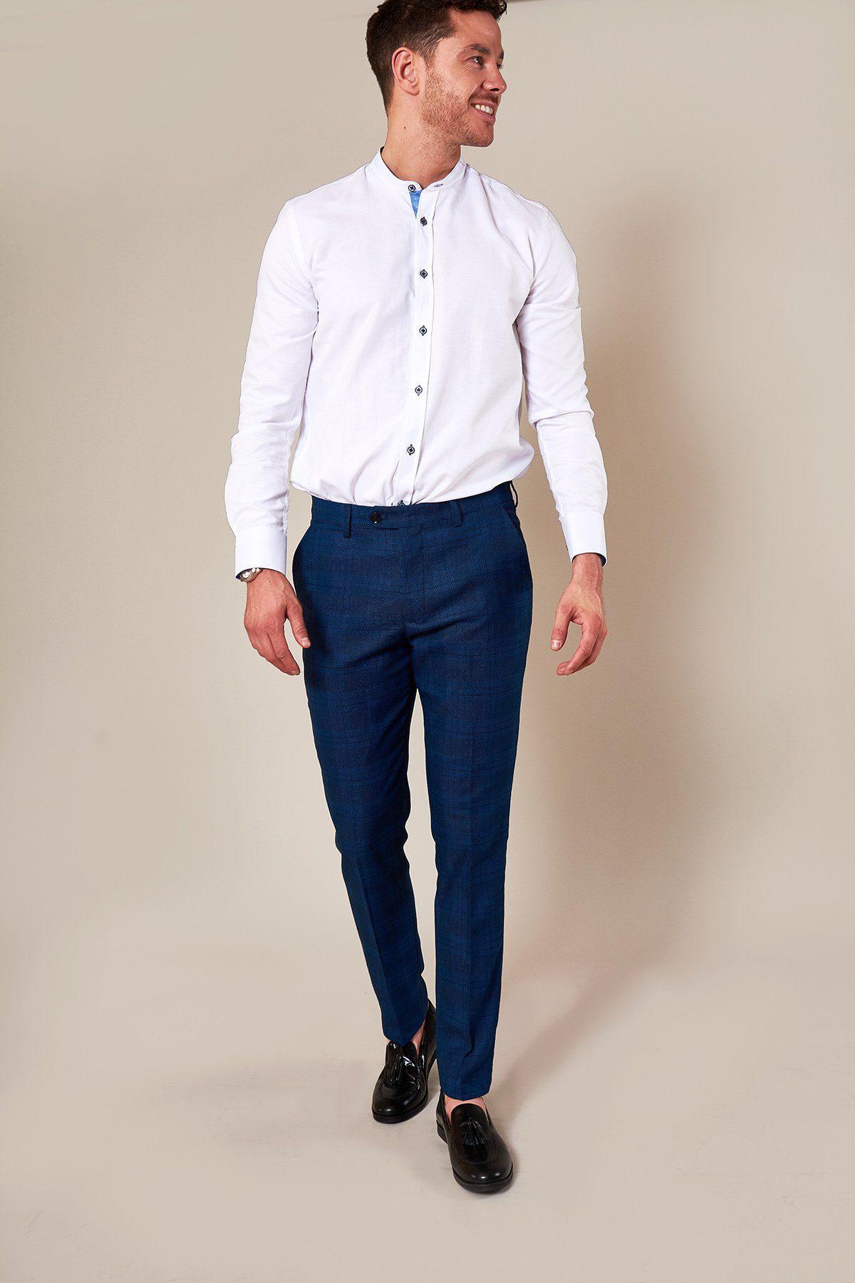 A man stands smiling to the side against a plain beige background, wearing a white button-up shirt, marcdarcy JERRY Skinny Fit Blue Check Trousers, and black loafers.