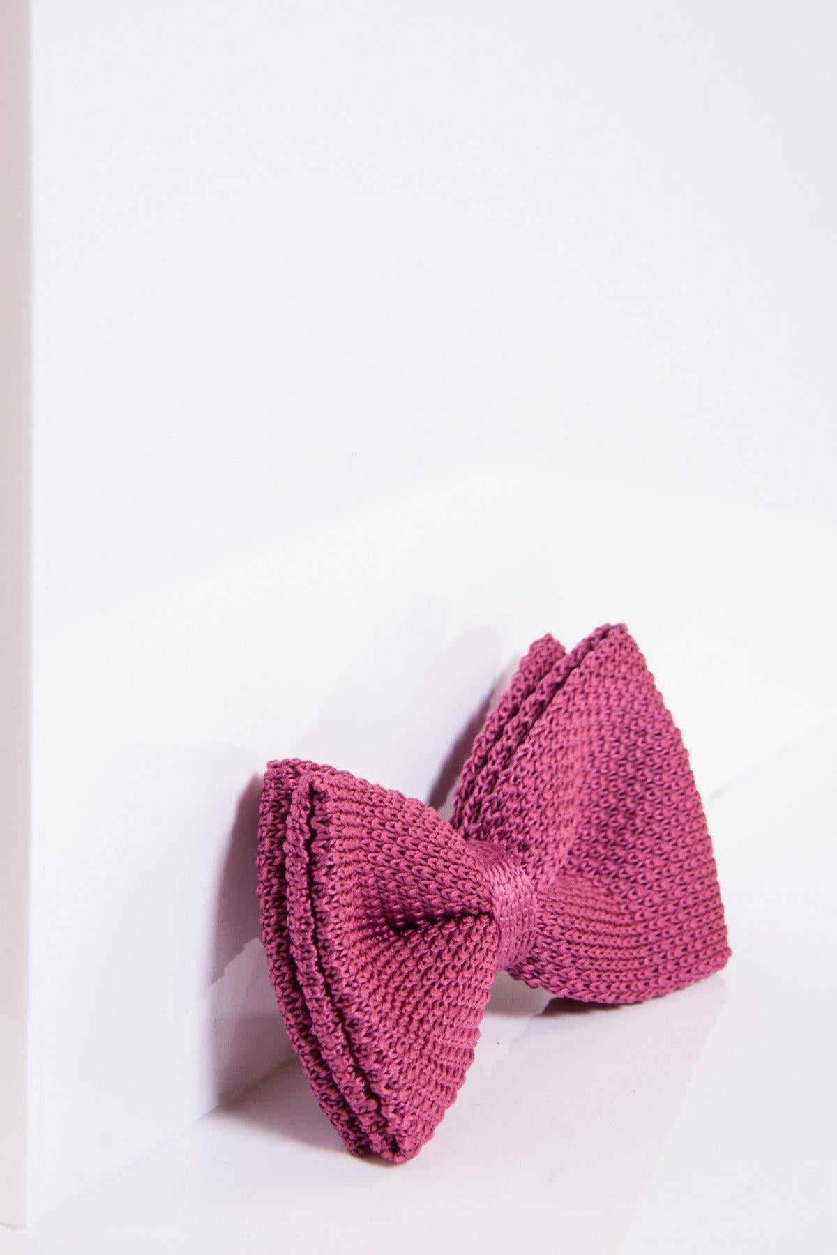 The marcdarcy KB - Knitted Double Layer Bow Tie In Berry, featuring a rich textured finish in deep pink, rests on a white surface and is angled to the right against a white backdrop.