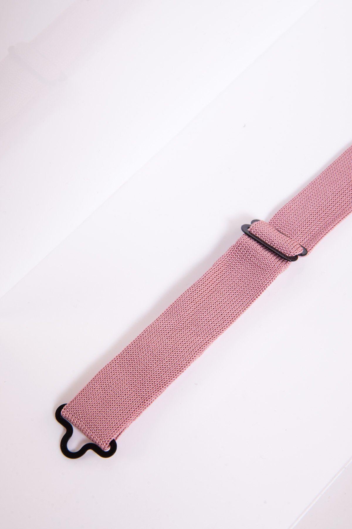 A close-up of the marcdarcy KB Knitted Double Layer Bow Tie in Blush Pink shows its pink woven strap, black metal hardware, adjustable slider, and hook at one end, laid diagonally on a white surface.