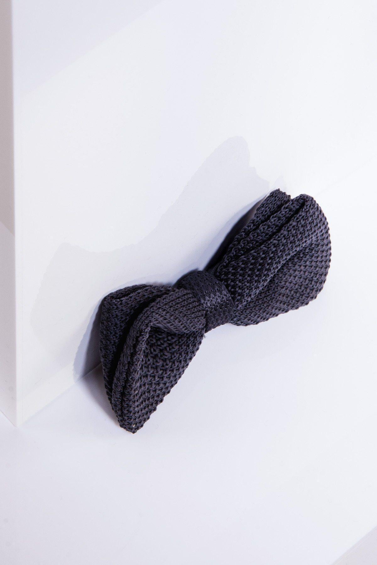 The marcdarcy KB - Knitted Double Layer Bow Tie in Mid Grey sits on a white minimalist background, its textured design and soft lighting creating an elegant contrast—ideal for sophisticated evening wear.