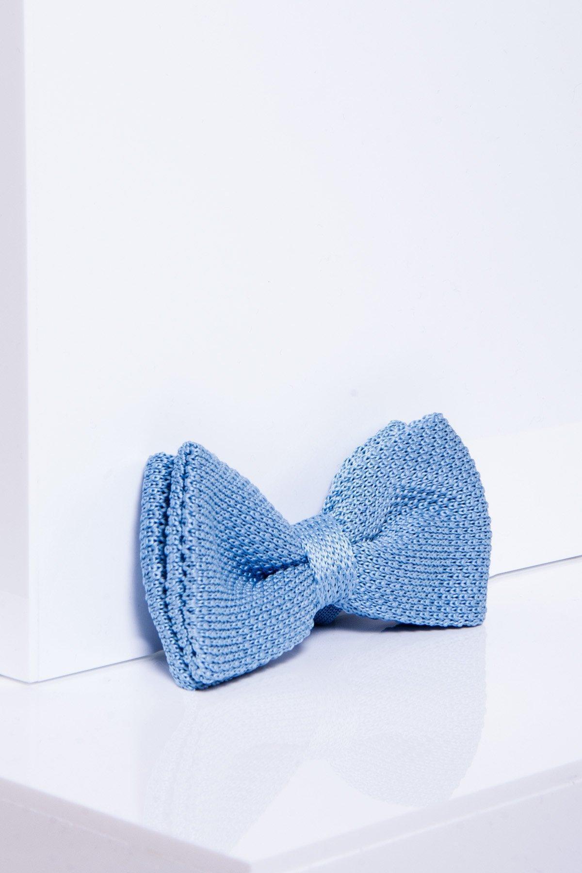 The marcdarcy KB - Knitted Double Layer Bow Tie In Sky Blue rests on a glossy white surface with soft shadows and a minimalist backdrop—an ideal men's accessory for spring.