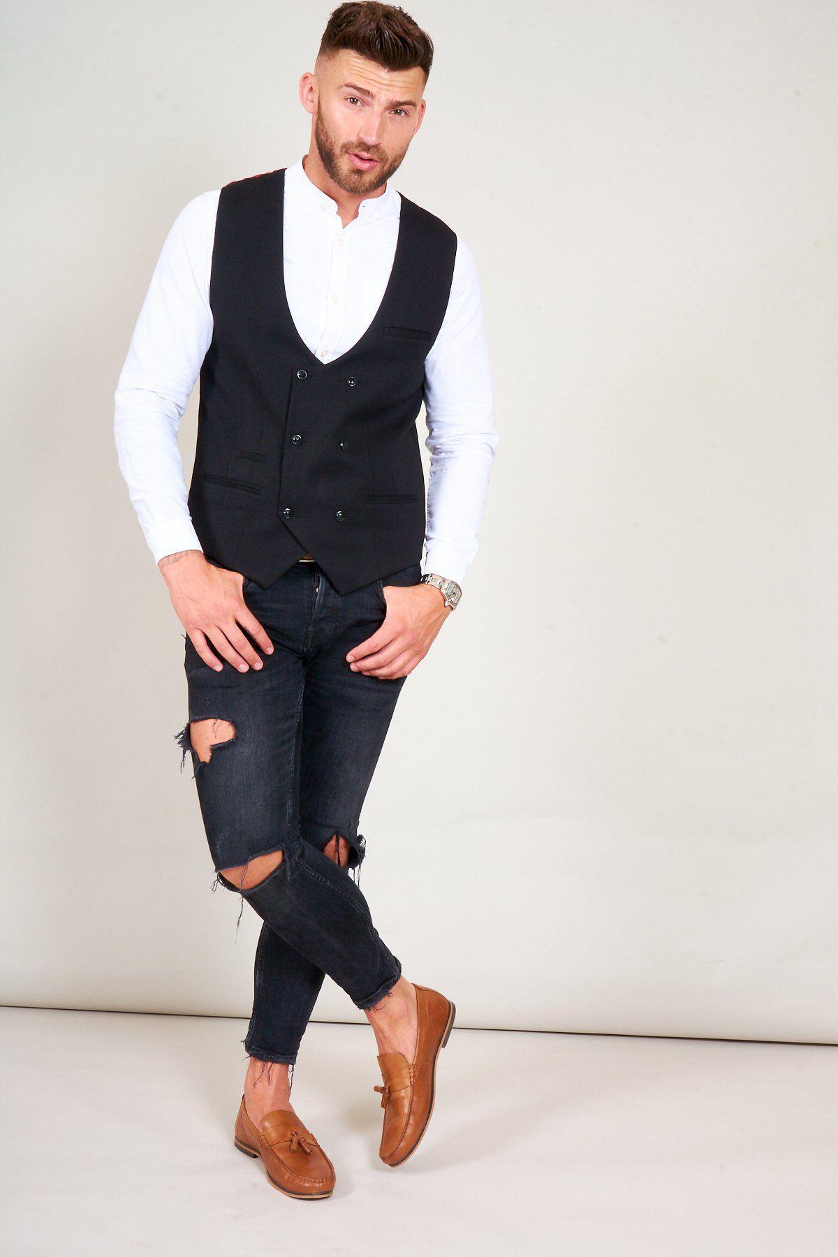 A man poses with his hands in his pockets, wearing a white collared shirt, ripped black jeans, brown loafers, and the marcdarcy KELLY Black Double Breasted Waistcoat.