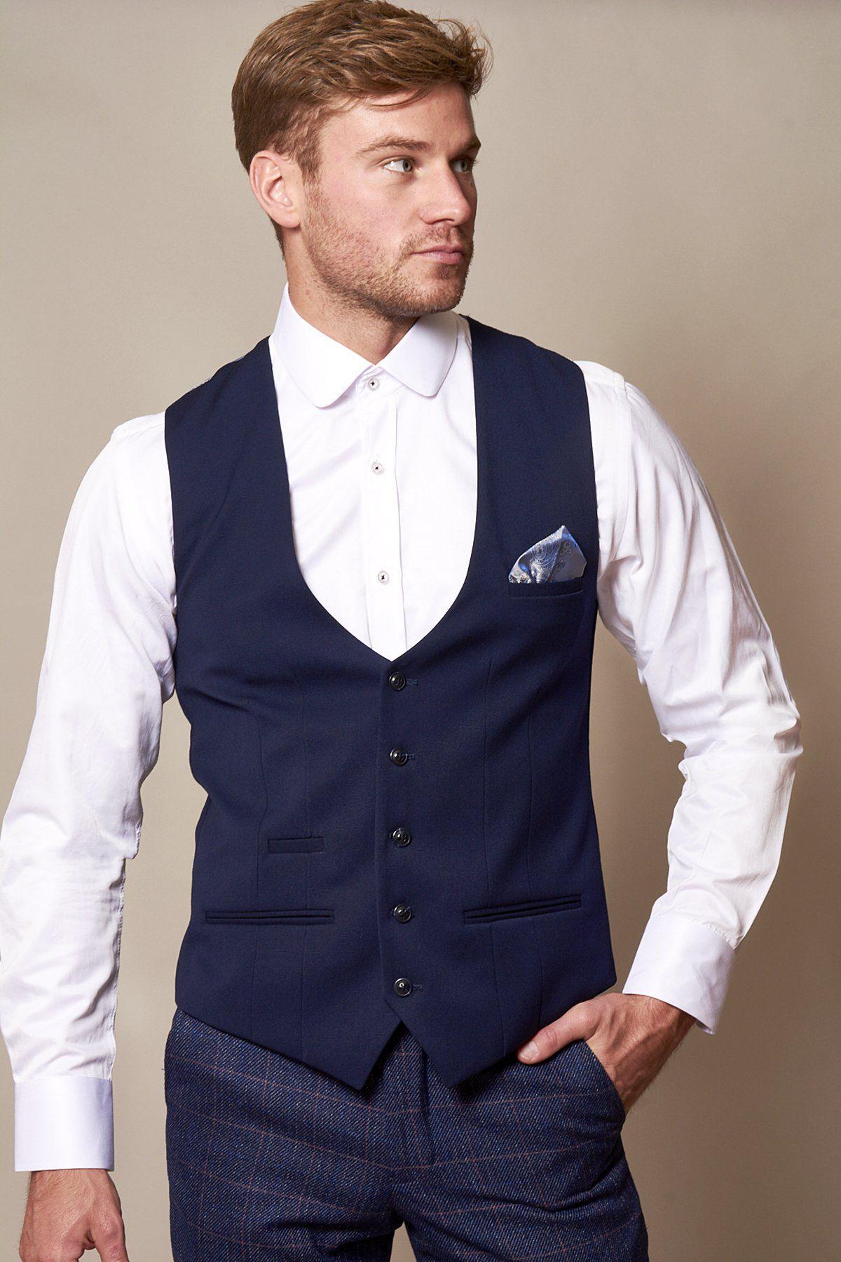 A man in a slim fit white dress shirt and the marcdarcy KELLY Royal Blue Single Breasted Waistcoat with pocket square looks to the side, one hand in his pocket, against a plain background.
