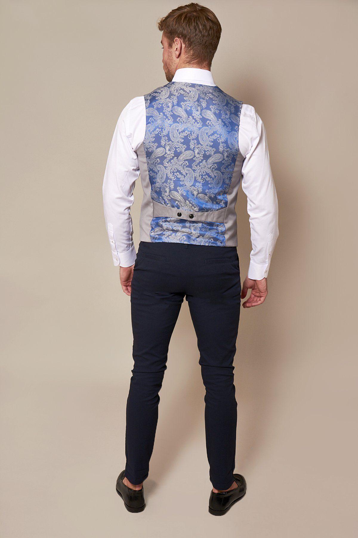 A man faces away, dressed in a white shirt, navy pants, black shoes, and the marcdarcy KELLY Silver Grey Single Breasted Waistcoat with a belt detail at the back, set against a plain beige background.