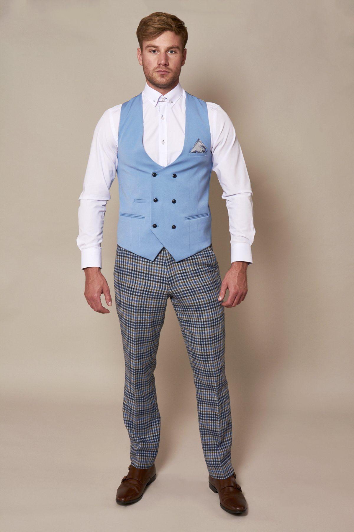 A man wears the marcdarcy KELLY - Sky Blue Double Breasted Waistcoat over a white dress shirt with a patterned pocket square, paired with plaid trousers and brown double monk strap shoes.