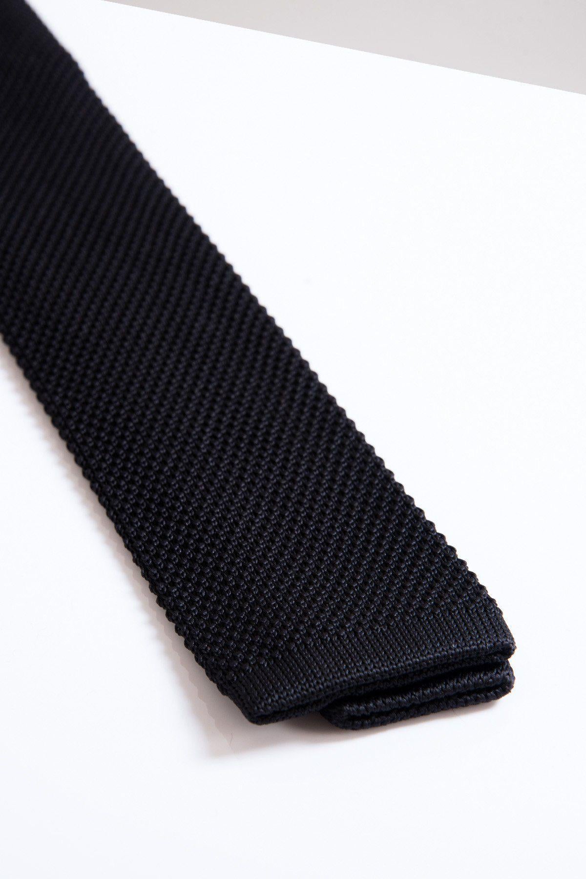 A close-up of the Accessory KT - Black Knitted Tie on a white surface highlights its square tip—a stylish choice for modern or formal occasions.