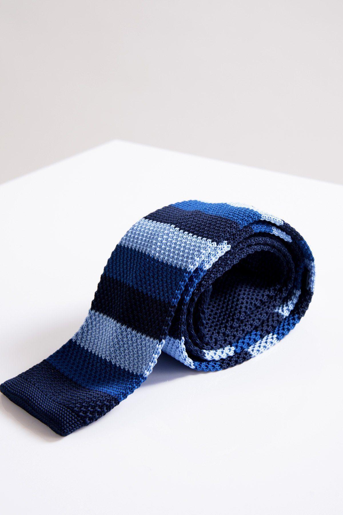 The Accessory KT - Blue Stripe Knitted Tie features dark navy, medium blue, and light blue stripes—ideal for smart office wear. Presented rolled up on a white surface with a light grey background.