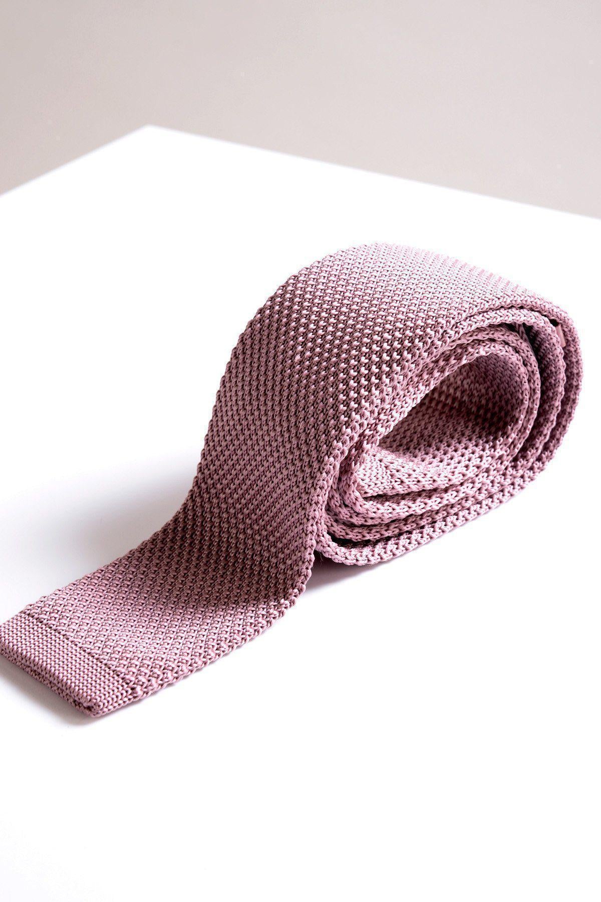 The KT - Blush Pink Knitted Tie by Accessory is rolled on a white surface with a soft background—an elegant men's fashion piece, perfect as a wedding accessory.