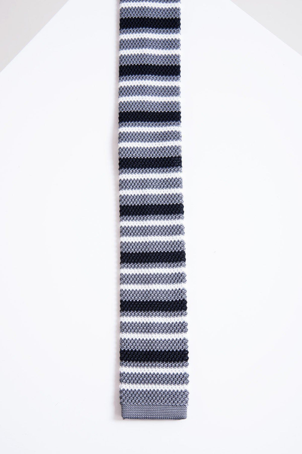 The Accessory KT - Grey Stripe Knitted Tie features horizontal black, gray, and white stripes on lightweight fabric, displayed flat against a white geometric background.