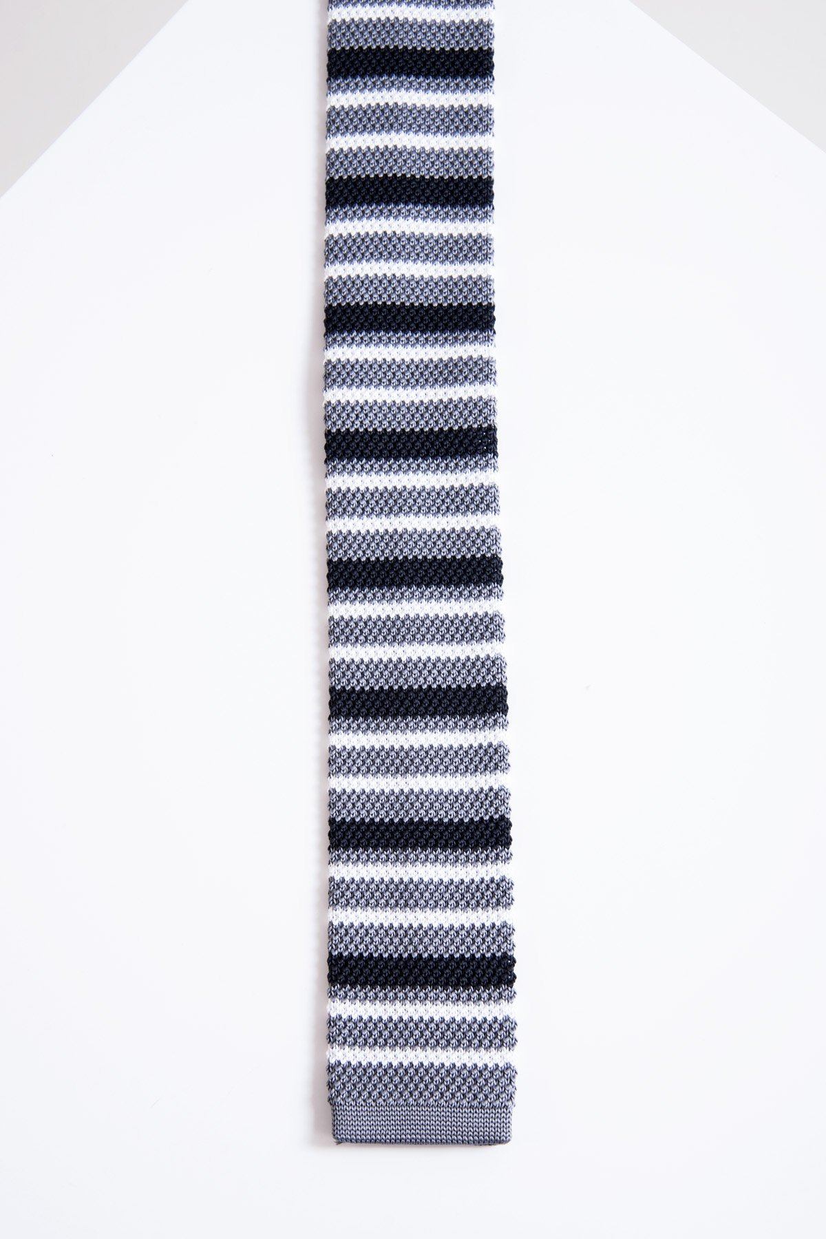 The Accessory KT - Grey Stripe Knitted Tie features horizontal black, gray, and white stripes on lightweight fabric, displayed flat against a white geometric background.