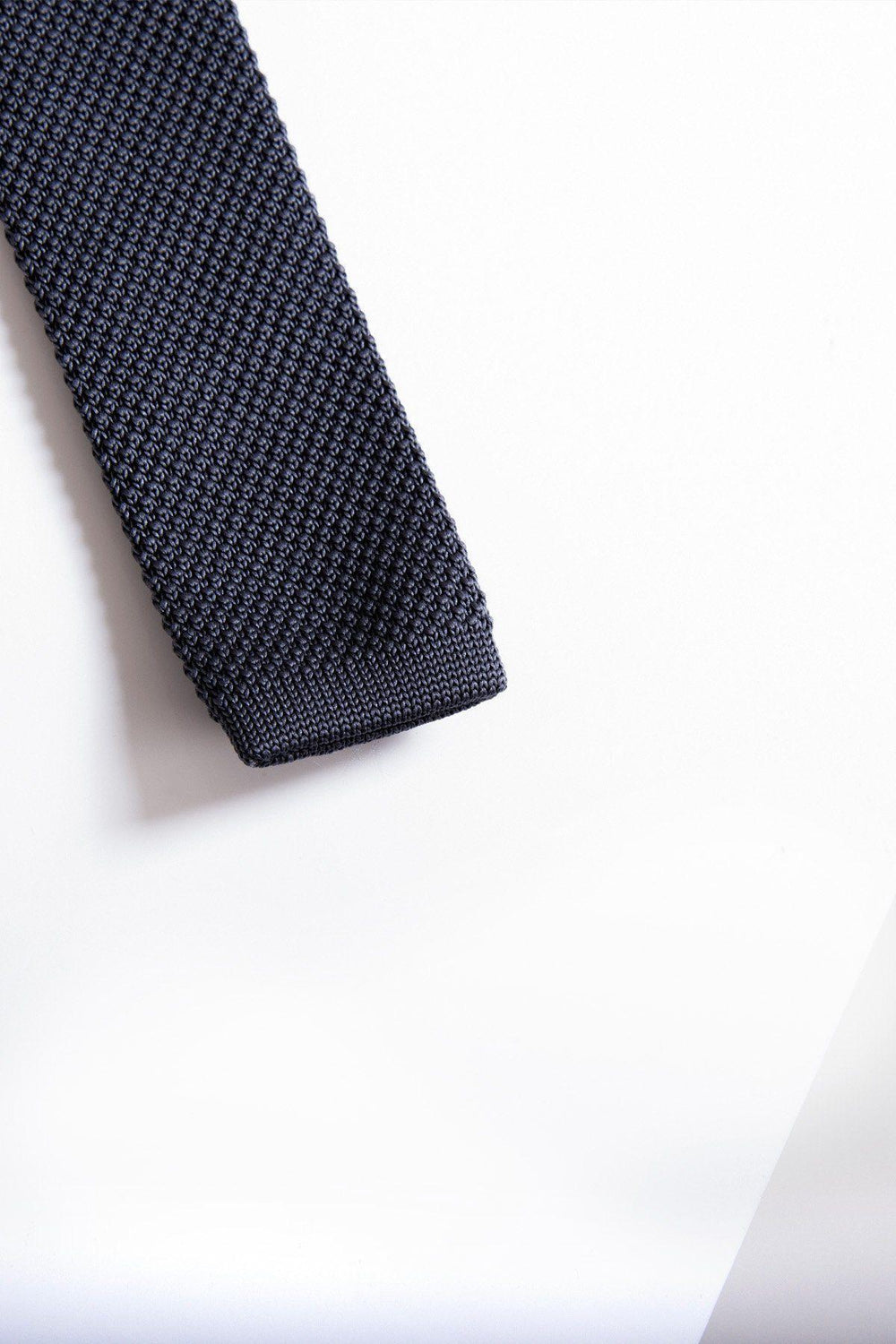 A close-up of the end of the Accessory KT - Mid Grey Knitted Tie, featuring a modern textured knit design, displayed on a white background.