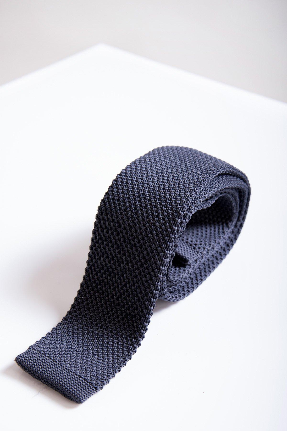 The KT - Mid Grey Knitted Tie by Accessory features a modern knitted design, neatly rolled and displayed on a white surface with a plain background—ideal for pairing with an office suit.