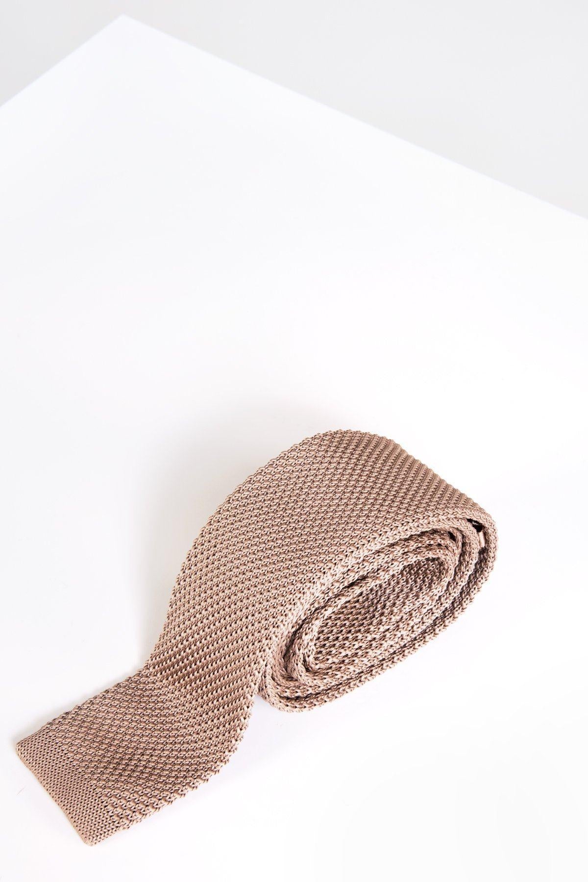 The KT - Oak Knitted Tie by Accessory features a beige oak hue and textured design, rolled up on a white surface with a minimalistic background—ideal for enhancing your wedding style.