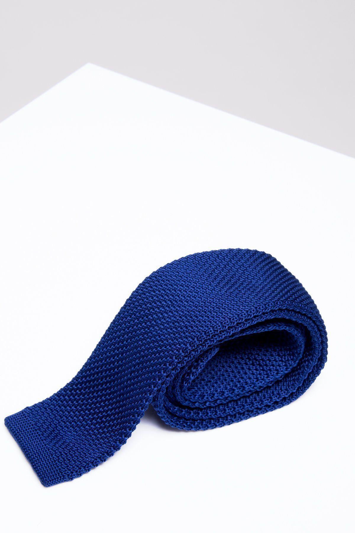 The KT - Royal Blue Knitted Tie by Accessory is neatly rolled and displayed on a white surface with a light gray background, making it the perfect work suit accessory.