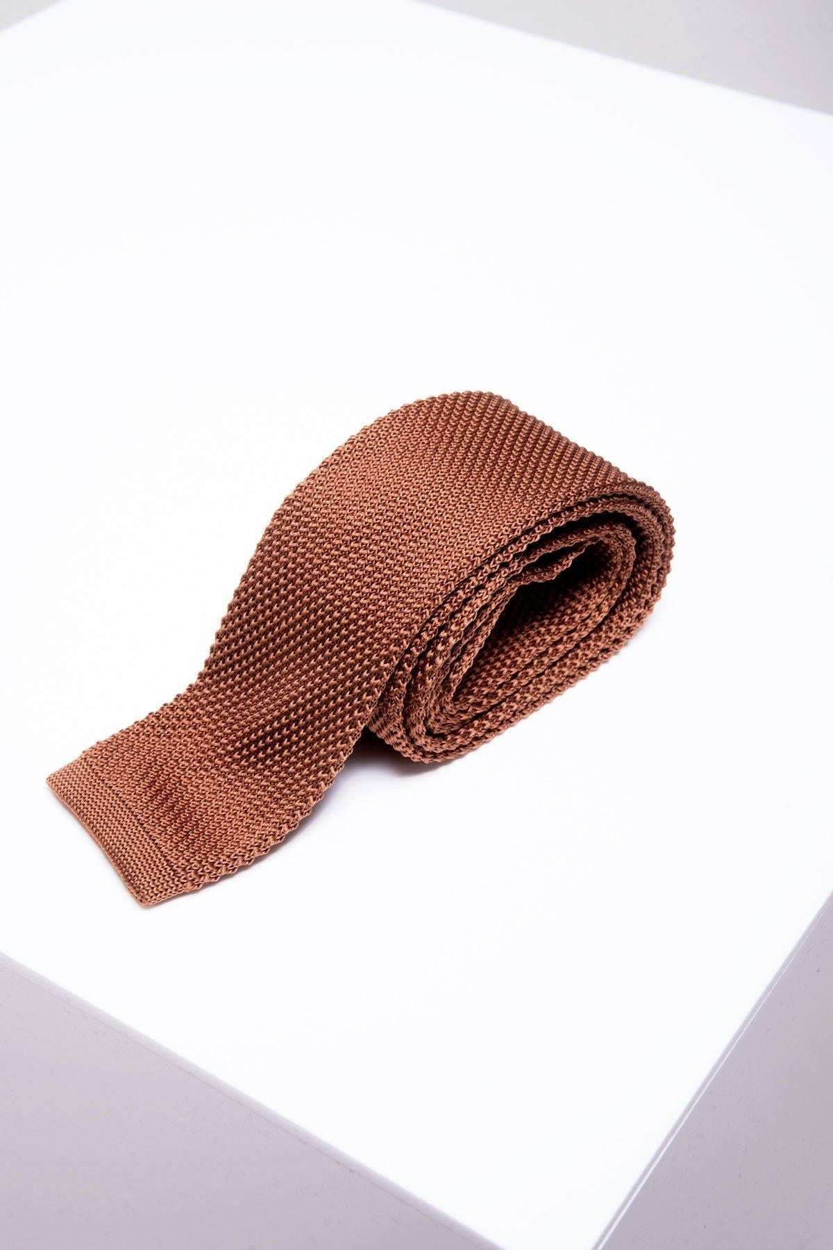 The KT - Rust Knitted Tie by Accessory, featuring a modern textured design, is neatly rolled and displayed on a clean white surface.