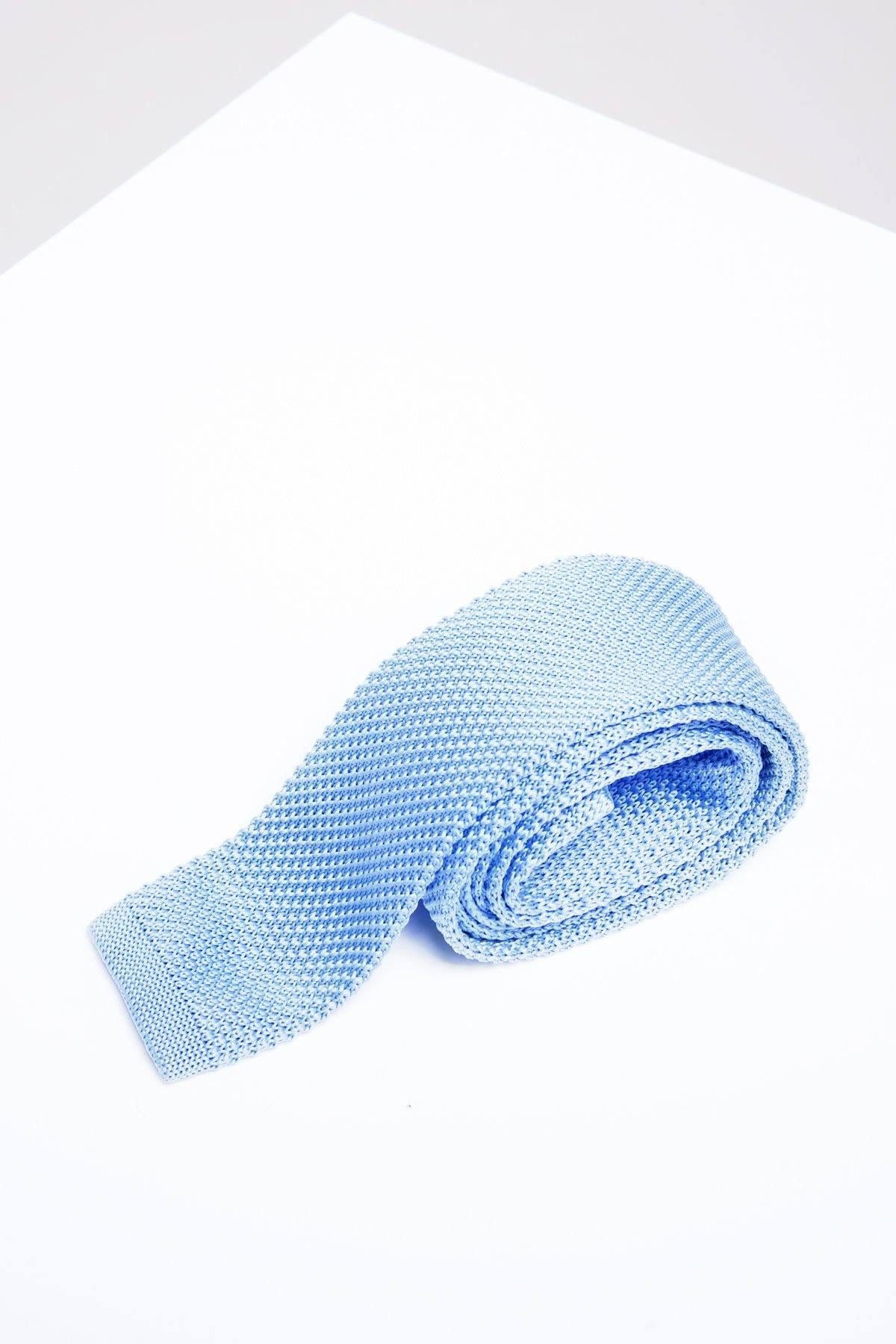 The Accessory KT - Sky Blue Knitted Tie, ideal for spring and summer, is rolled up on a white surface.