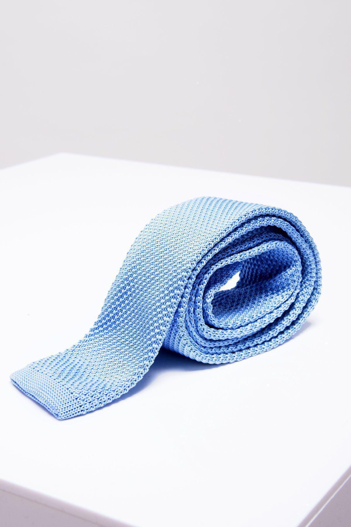 The KT - Sky Blue Knitted Tie by Accessory features a modern textured design and is presented rolled up on a white surface against a plain light background.