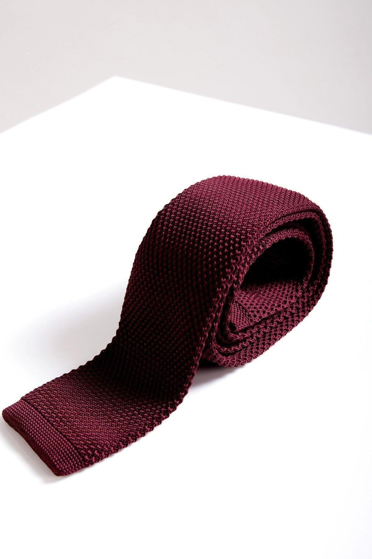 The KT - Wine Knitted Tie by Accessory features a textured design and is neatly rolled on a white surface—ideal for enhancing your wedding style.