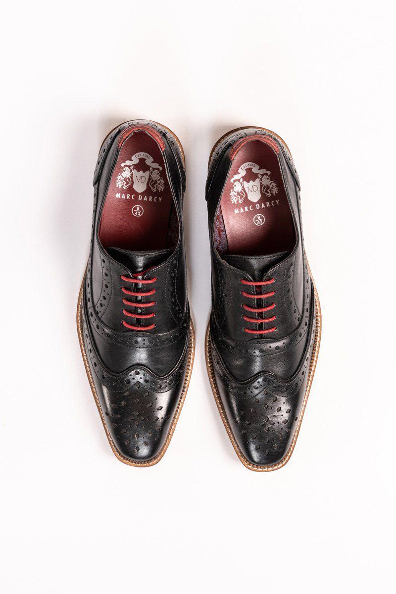 The Marc Darcy LARKIN black full grain leather brogue shoes have decorative perforations, red laces, brown soles, and insoles with white Marc Darcy branding on a burgundy background. Viewed from above.