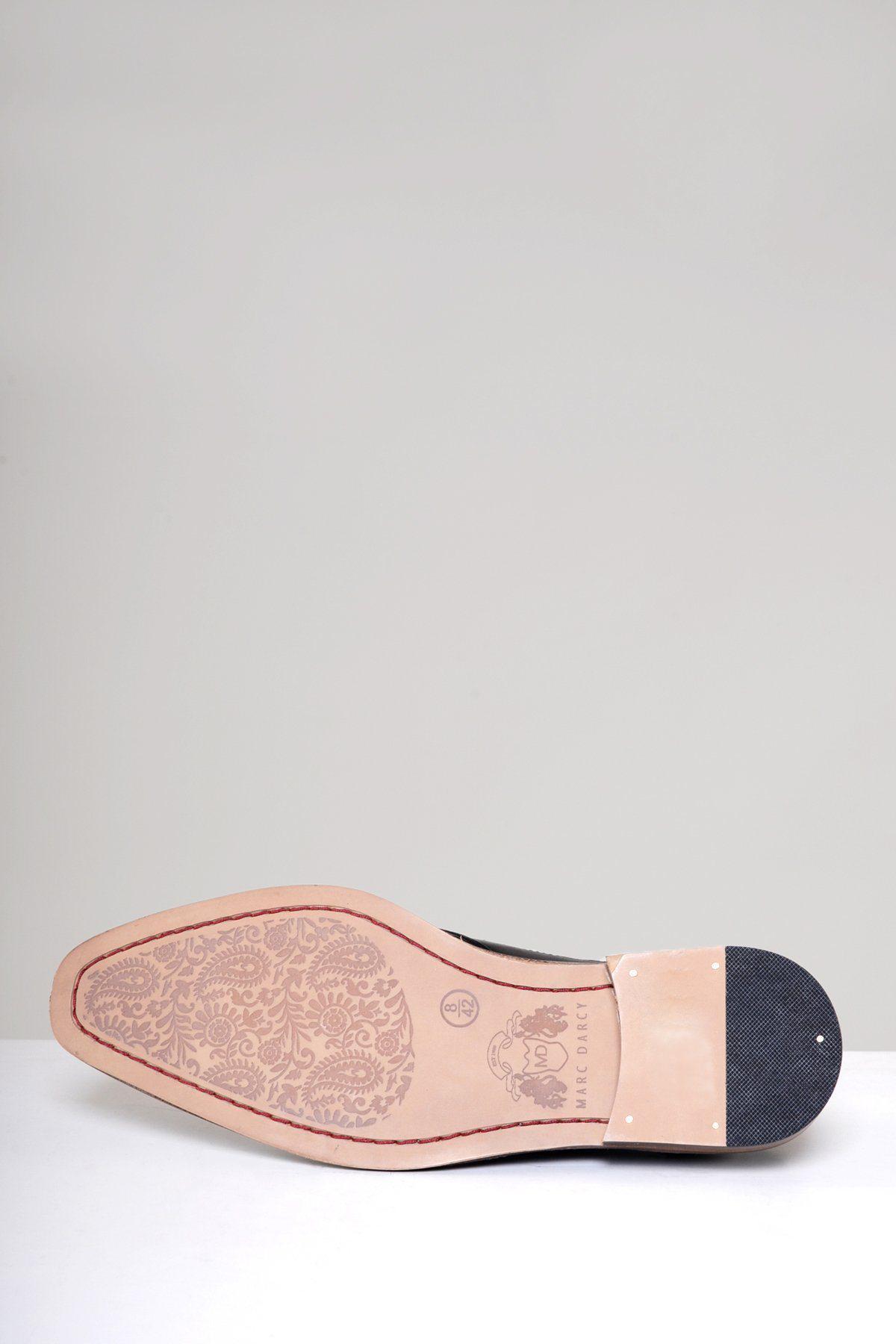 A close-up of the Marc Darcy LARKIN Black Leather Brogue Shoe highlights its floral-patterned full grain leather sole and textured black heel, with the hand-crafted men's shoe placed on a white surface against a light gray background.