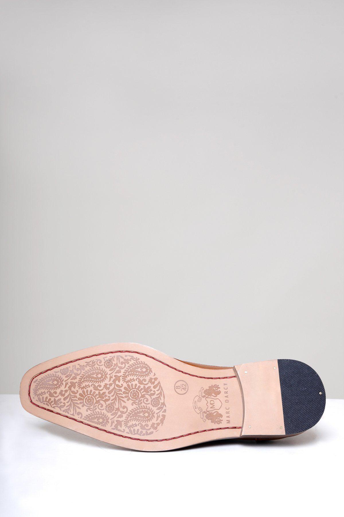 The image displays the sole of the Marc Darcy LARKIN mid tan leather brogue shoe, featuring full grain leather with floral forefoot etching, a textured dark heel, and a logo embossed by the arch for a classic look.