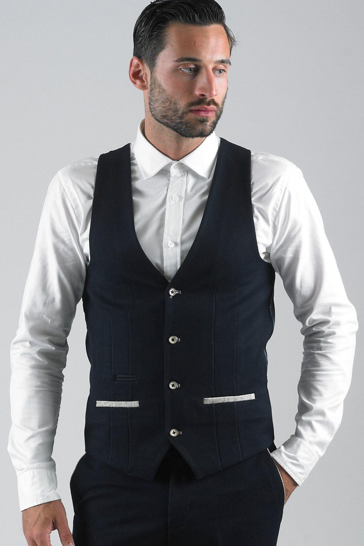 A man with dark hair and a beard wears the marcdarcy LEE WILL-Denim Look Navy Waistcoat over a white button-down shirt, with one hand in his pocket.