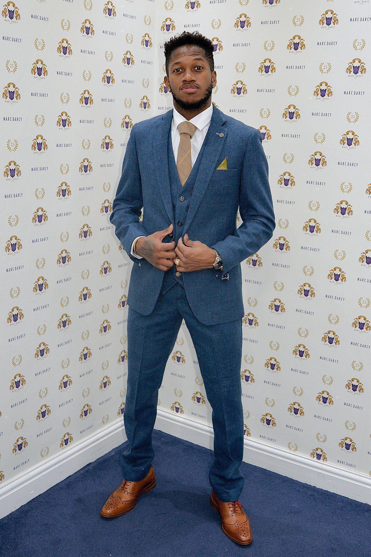 Fenerbahçe and Brazil midfielder Fred wears a marcdarcy Dion Blue Tweed Check Suit, posing confidently against a repeating logo wall and looking at the camera while holding his jacket with both hands.