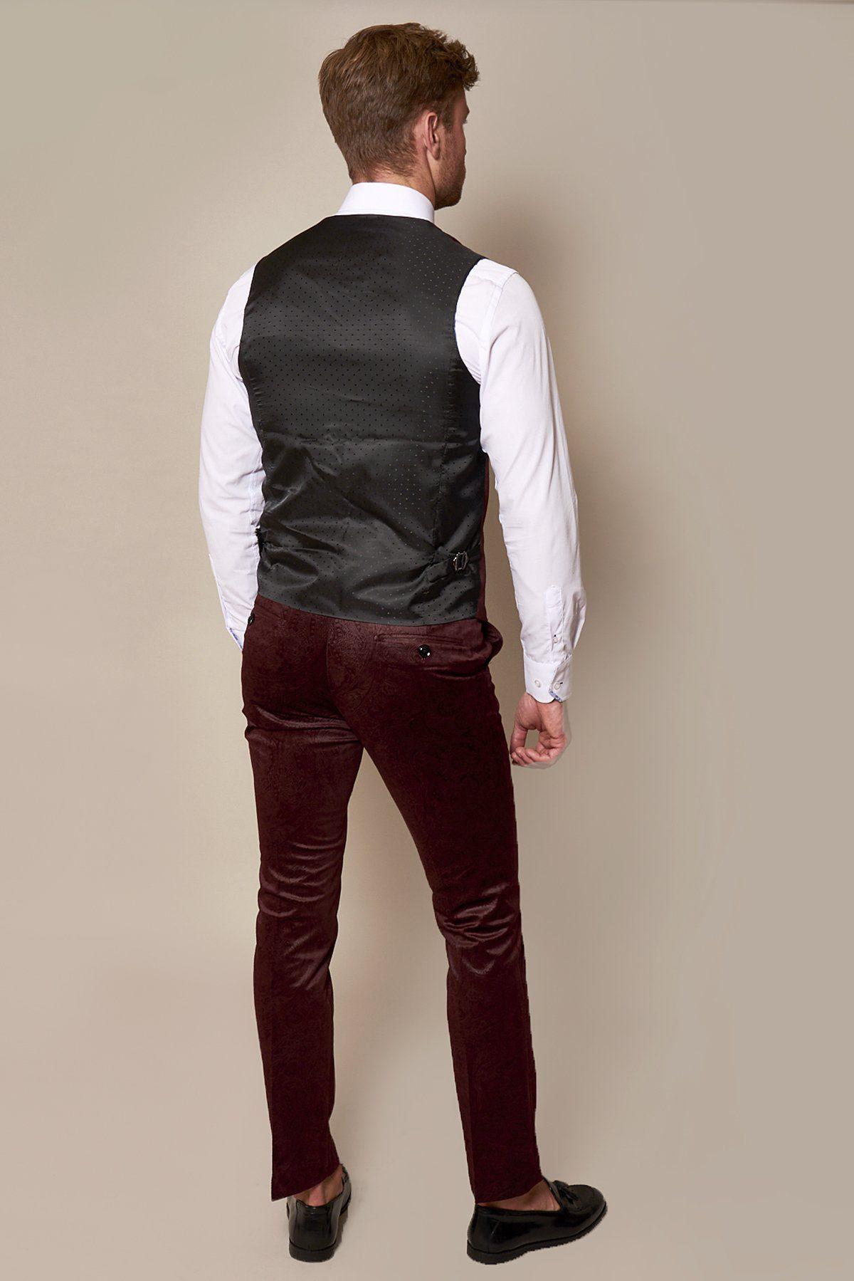 A man stands with his back to the camera, wearing a white shirt, black waistcoat, Marc Darcy Simon Wine Velvet Suit as seen on Fenerbahçe and Brazil midfielder Fred, and black shoes against a plain beige background.