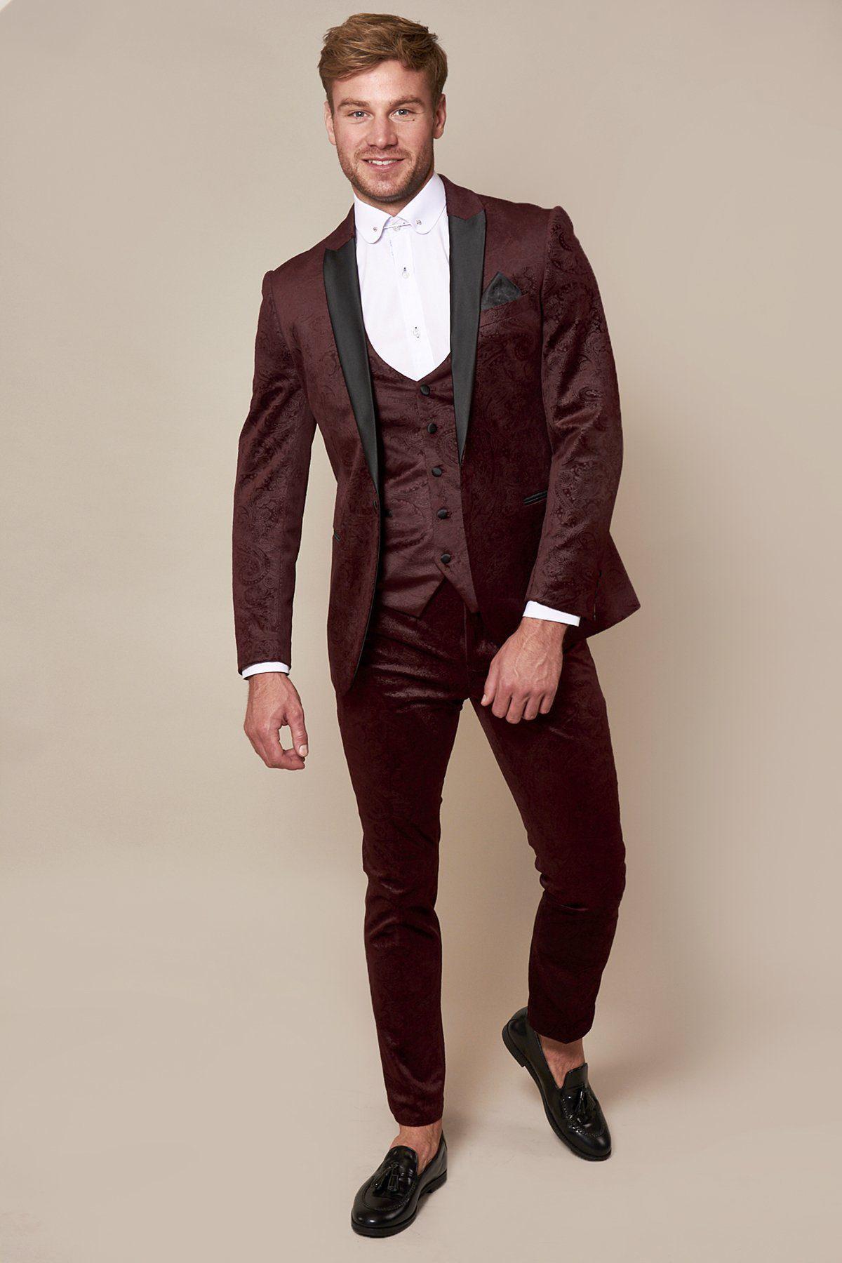 Fenerbahçe and Brazil midfielder Fred smiles against a beige background wearing a Marc Darcy Simon Wine velvet suit, styled with a white shirt, black pocket square, and black loafers. He has light brown hair and a beard.