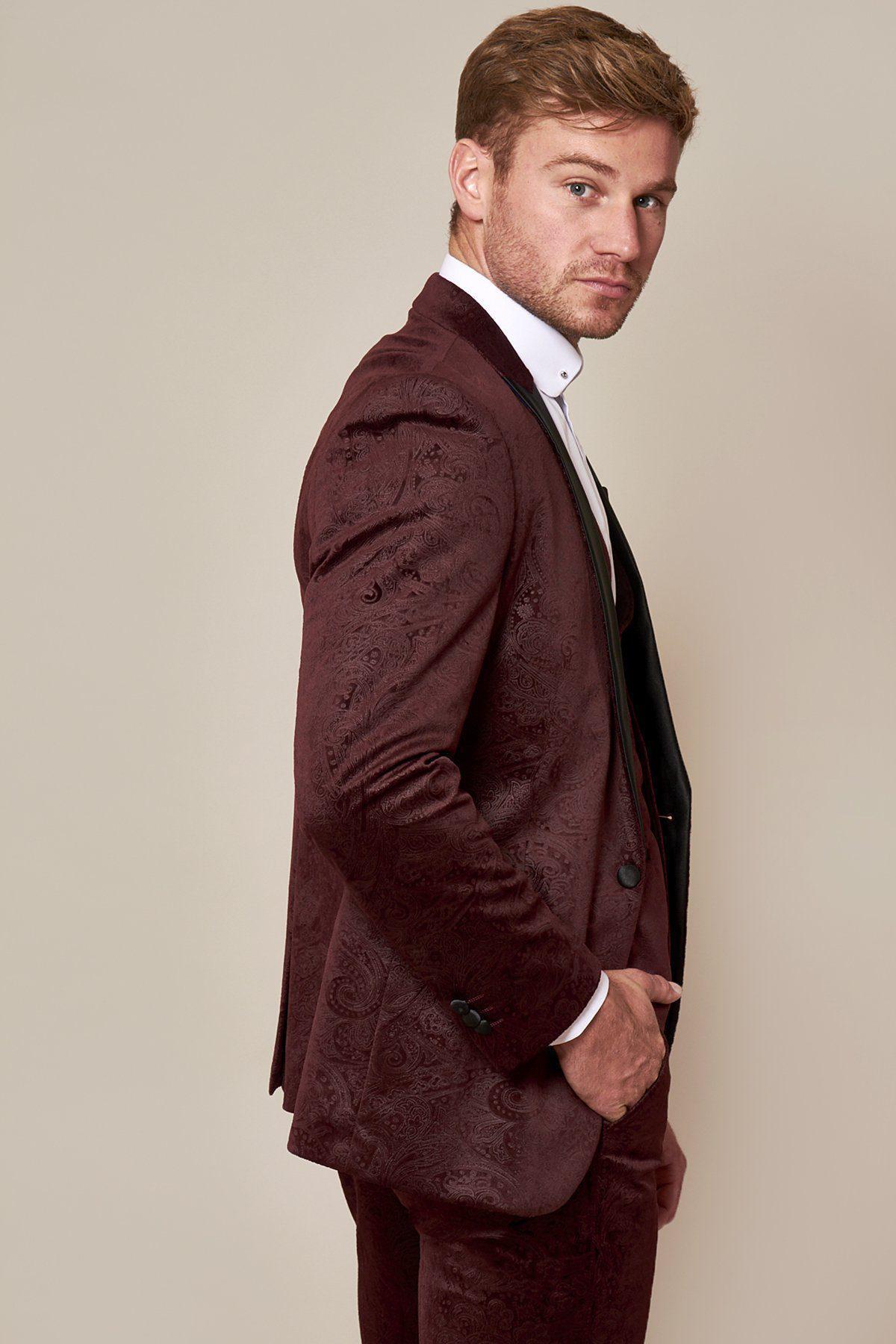 Fenerbahçe and Brazil midfielder Fred, with light brown hair and a beard, wears a Marc Darcy Simon wine velvet suit, standing in profile with one hand in his pocket, looking over his shoulder against a plain background.