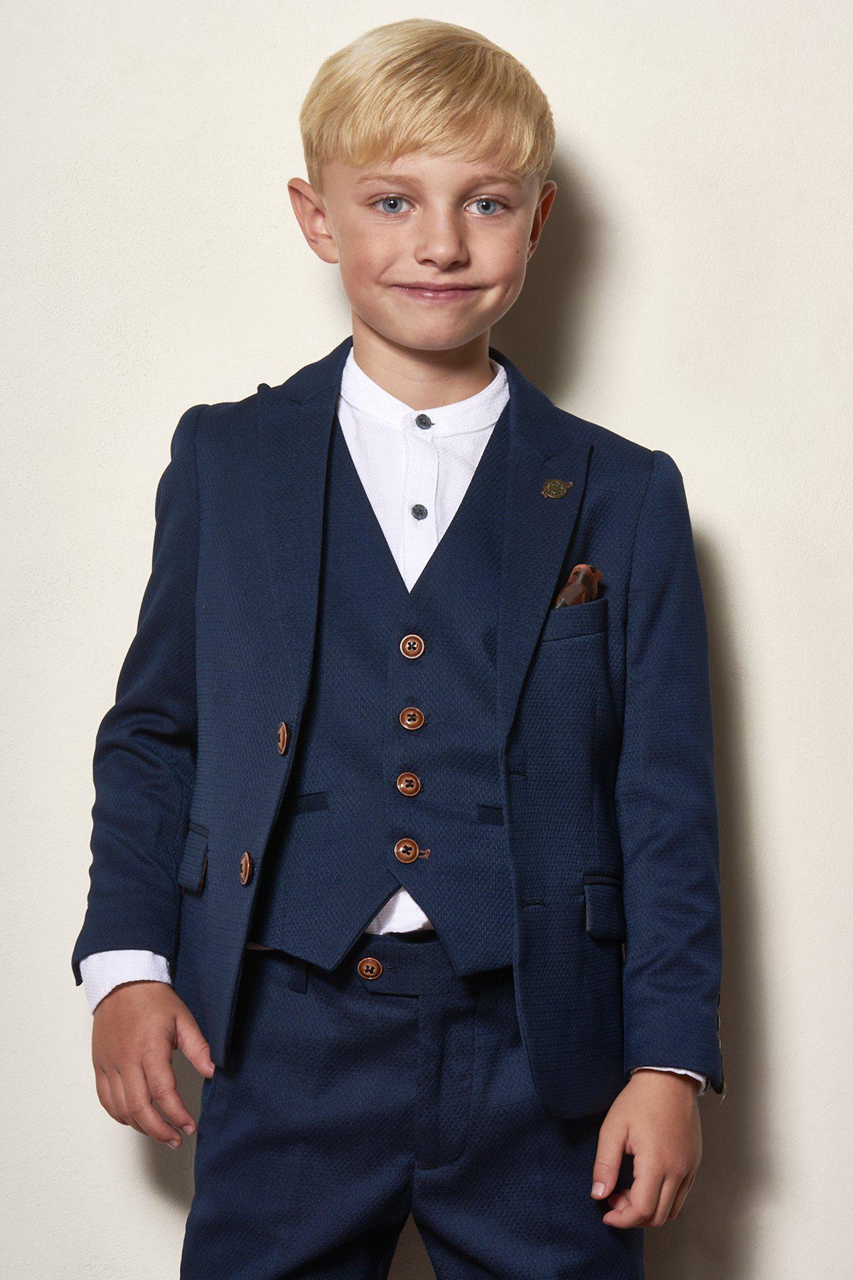 A young boy with blonde hair smiles while wearing the marcdarcy Matching Father & Son Men’s MAX Royal Blue Three Piece Suit, standing against a light background.