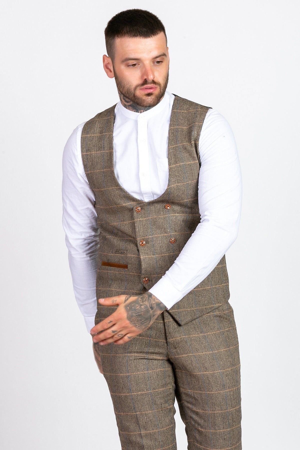A man with short dark hair, a beard, and tattoos on his hand and arm wears the marcdarcy MAX navy suit with TED waistcoat. He looks down to his left against a plain white background.